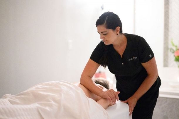 Massage therapist giving a facial massage to a client on a table in a bright spa room