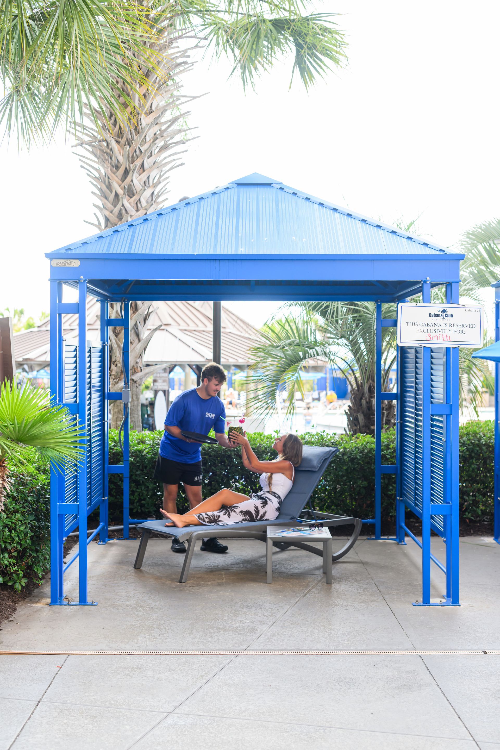 Blue tents and metal crowd-control barriers set up outdoors in a paved area