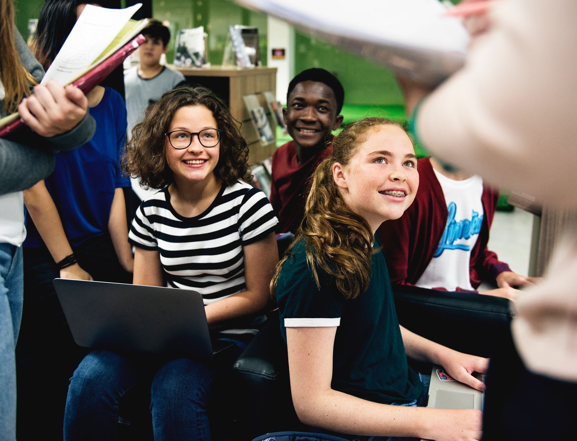 A group of young people are sitting on a couch with laptops.