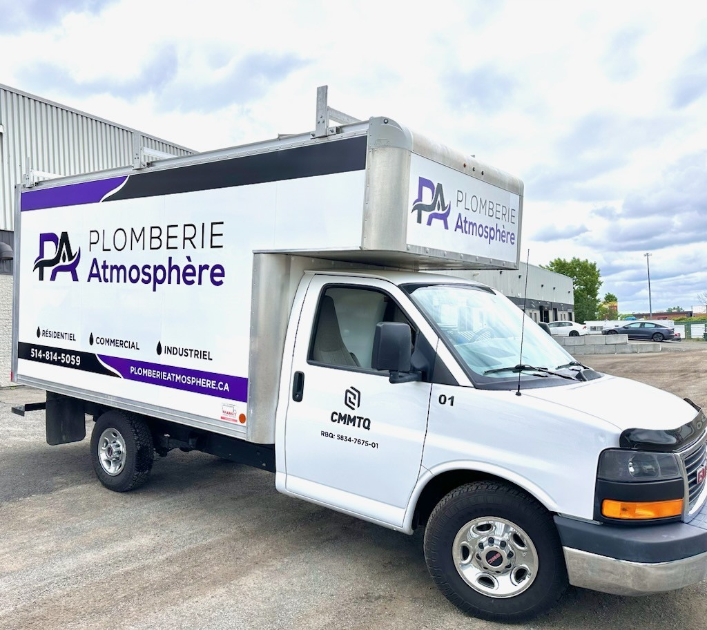 Un camion blanc avec le mot plomberie sur le côté est garé sur un parking.