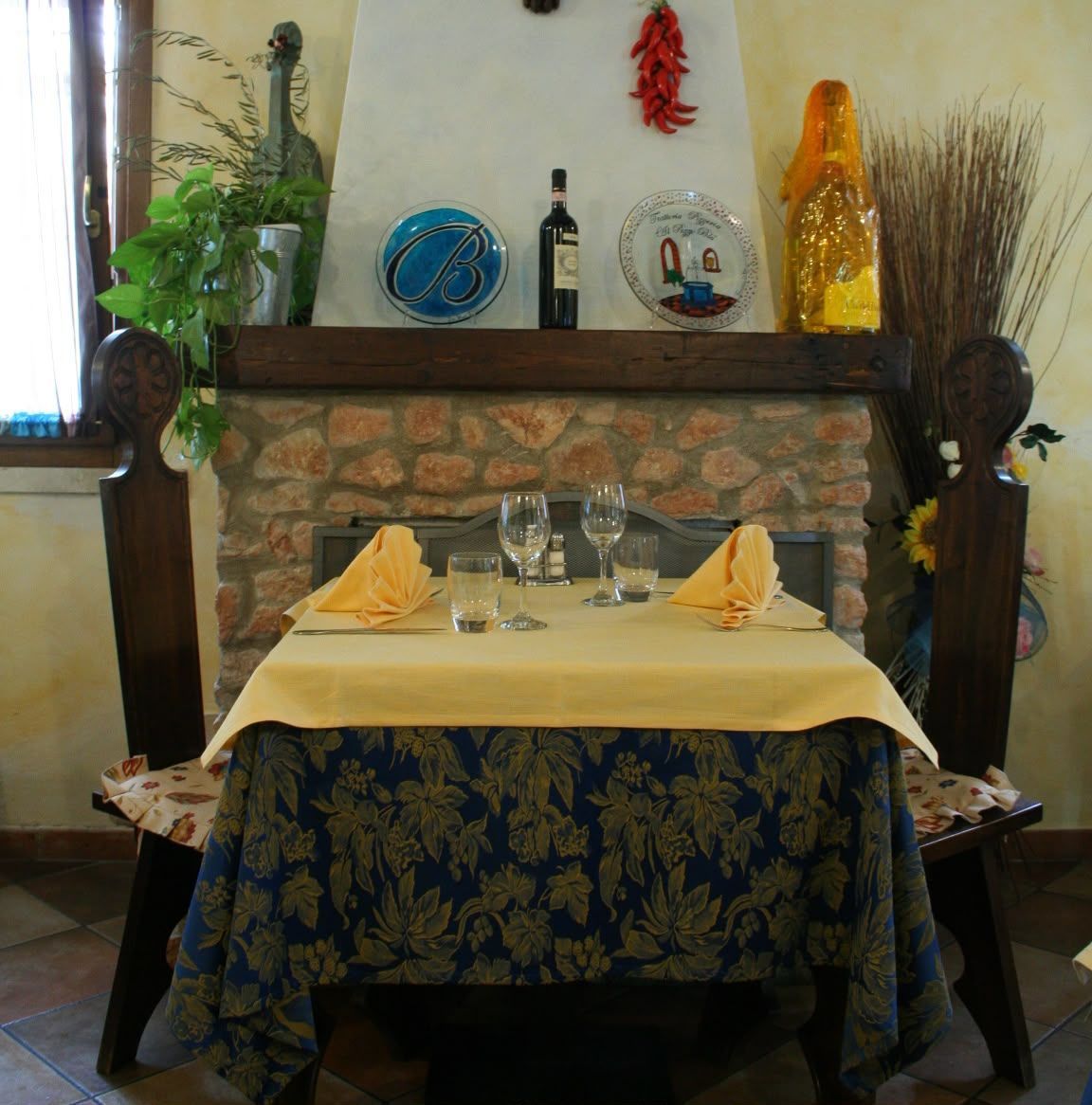 Accogliente tavolo da ristorante con tovaglioli piegati, bicchieri e decorazioni con camino in pietra sullo sfondo