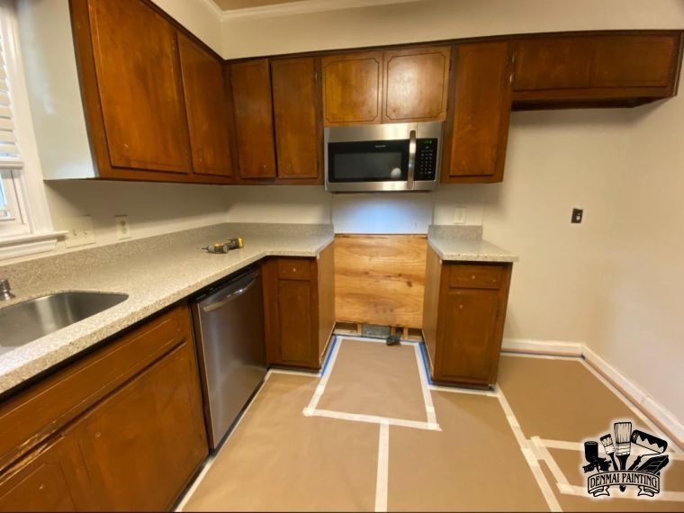 Empty kitchen with dark wood cabinets, countertop, microwave, and taped-off floor area under renovation.