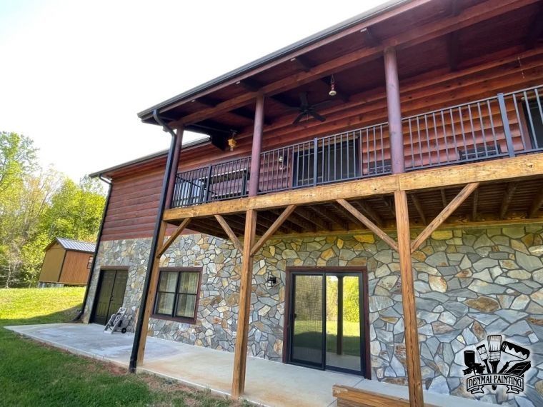 Rustic two-story house with stone lower level, wood upper siding, balcony, and covered patio