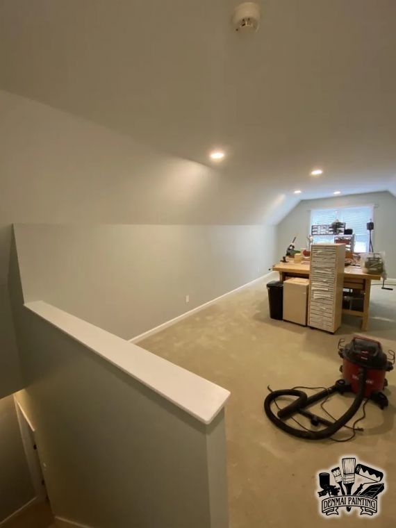 Empty hallway leading to a room under renovation, with a vacuum on the carpet and boxes in the background