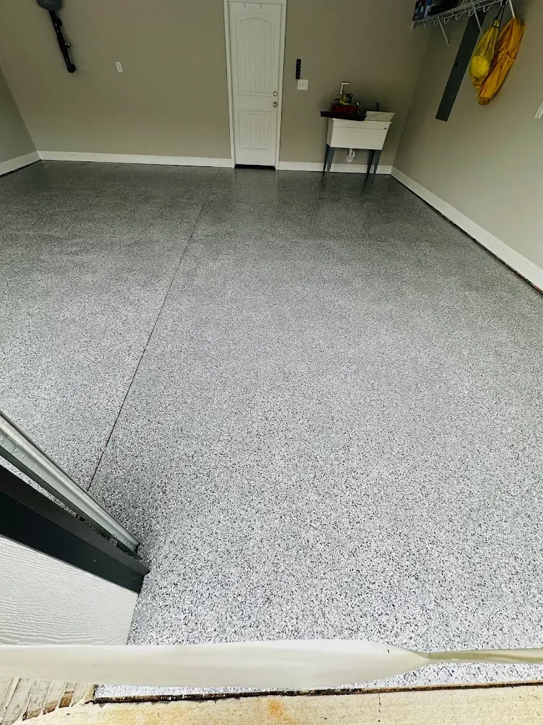 Small empty room with gray speckled flooring, white walls, and a table in the back corner.