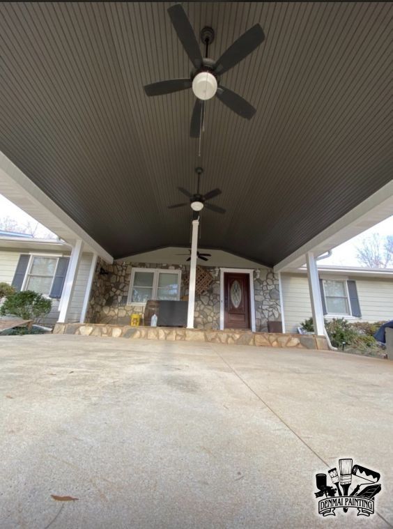 Covered front porch with two ceiling fans, stone columns, and a front door.