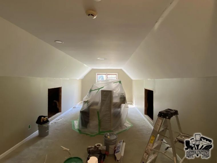 Long attic room under renovation with plastic-covered object, ladder, and tools on the floor.