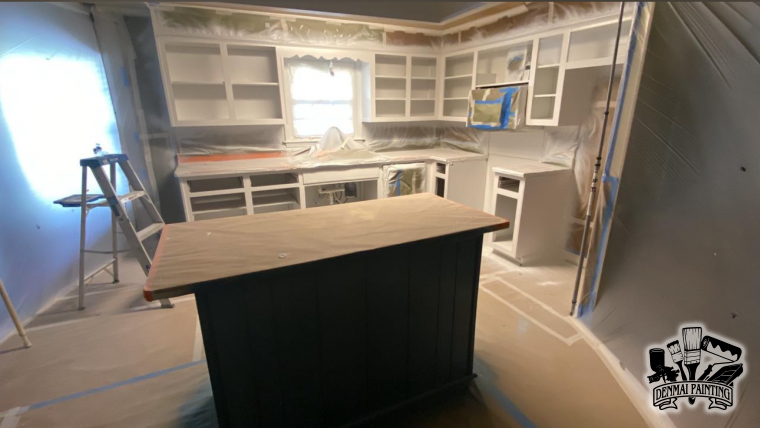 Kitchen with white cabinets, central island, and an unfinished, dusty floor under renovation