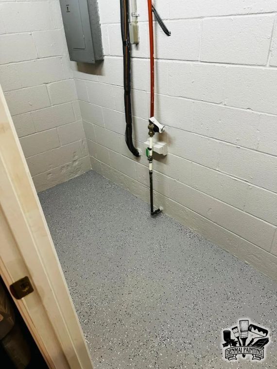 Small utility room with white cinderblock walls, gray epoxy floor, and exposed pipes and electrical panel.