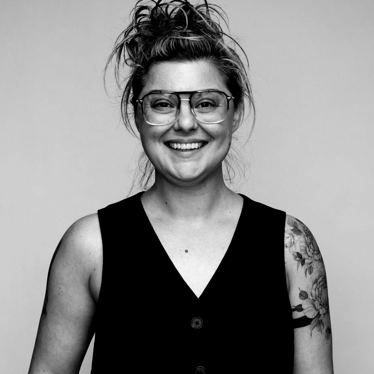 A woman with long hair and hoop earrings is smiling in a black and white photo.