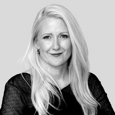 A woman with long hair and hoop earrings is smiling in a black and white photo.