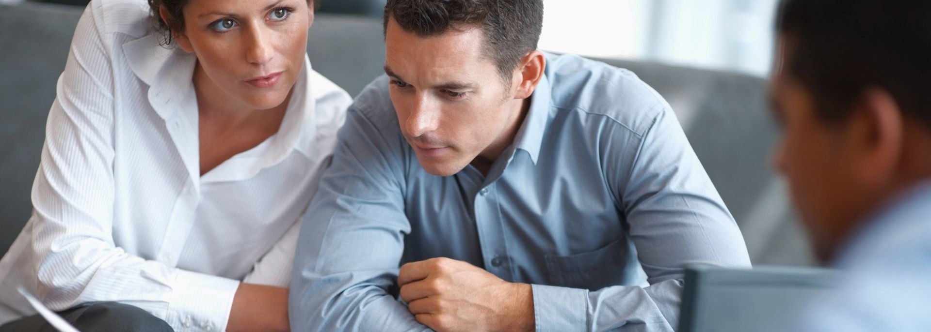Professional couple in business attire reviewing documents in a meeting with a consultant, discussing financial matters. Professional couple in business attire reviewing documents in a meeting with a consultant, discussing financial matters.