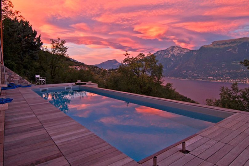 Piscina al tramonto davanti alle montagne e al Lago di Garda dopo il servizio di ristrutturazione piscine a Brescia e dintorni