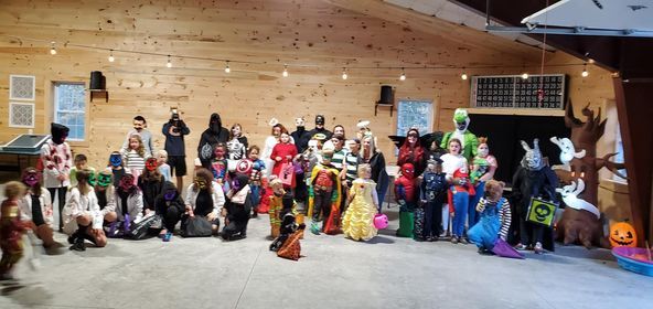 Costumed group posing in a wooden hall with a Christmas tree and holiday decorations