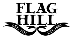 Black-and-white Flag Hill logo with “Lee, NH” and “Est. 1990” on ribbon banner