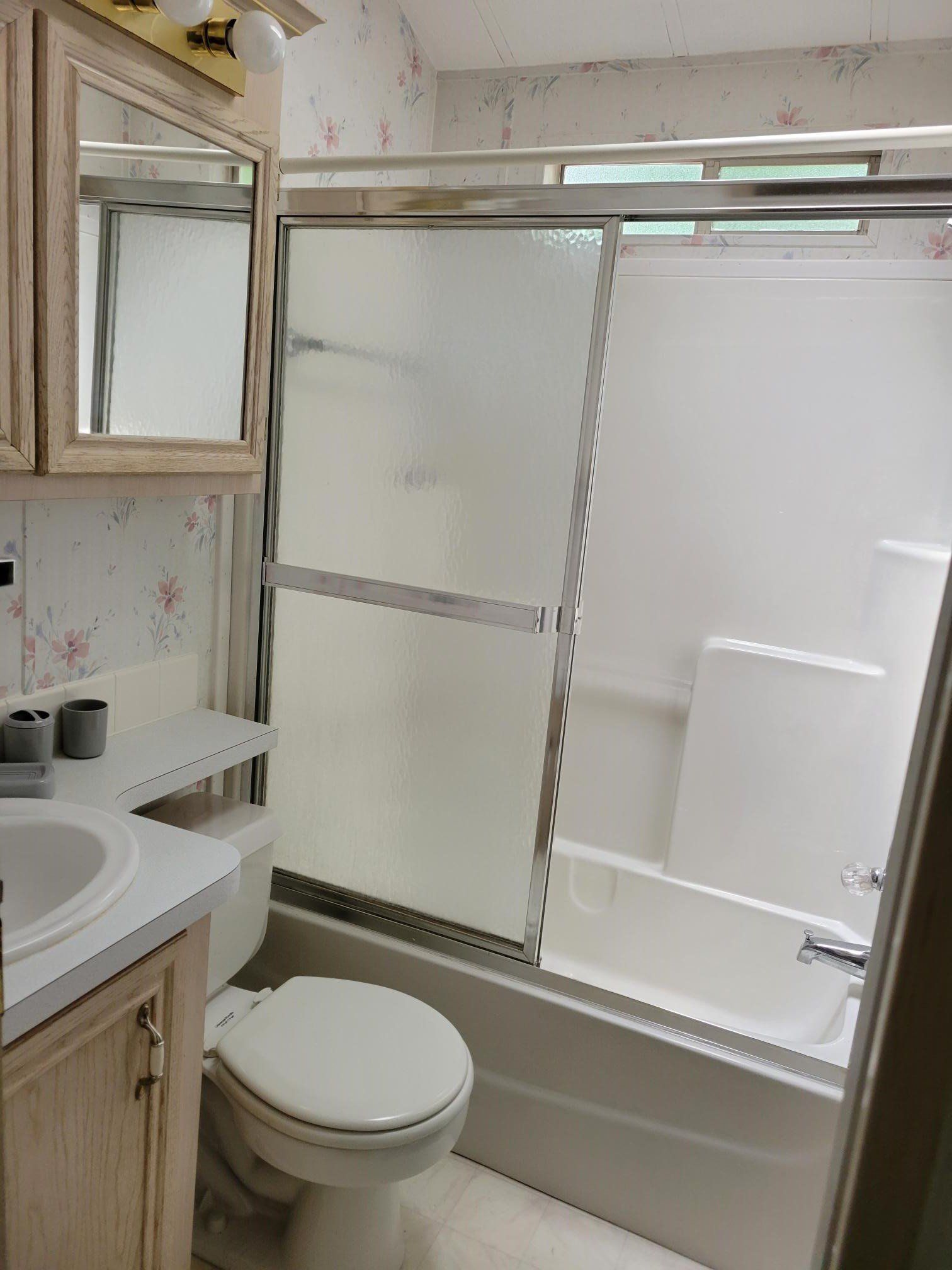 Small bathroom with sink, toilet, and bathtub with sliding glass shower doors.