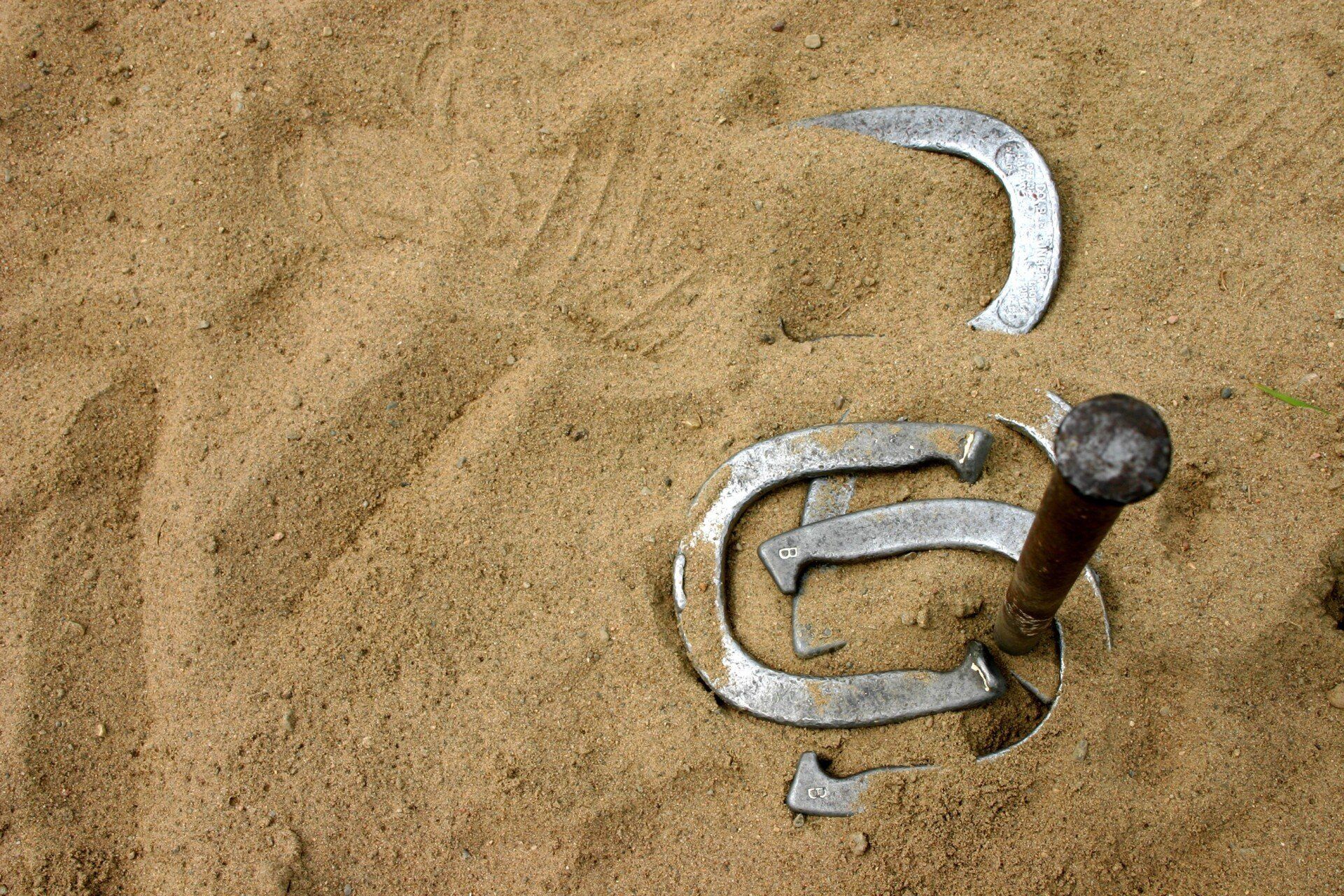 Metal sand mold of the Mercedes-Benz logo on beige sand with a small hammer nearby