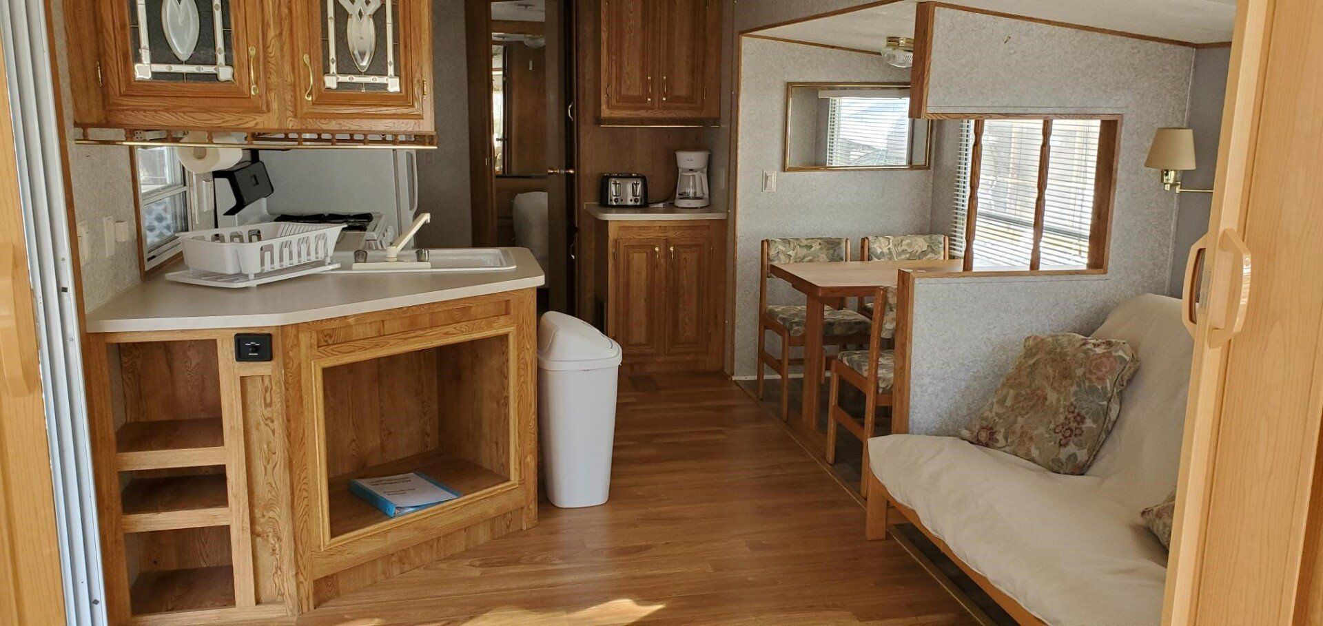 Cozy RV interior with wood cabinets, dining nook, and sofa by the window