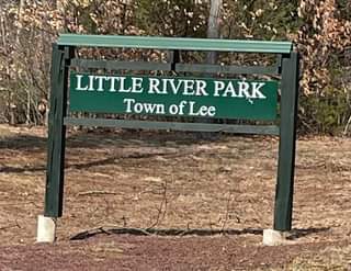 Sign for Little River Park, Town of Lee, on green posts in a wooded area