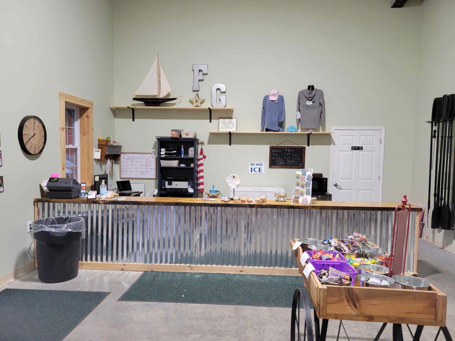 Indoor lobby with a long counter, shelves, wall clock, and a small display table of snacks.