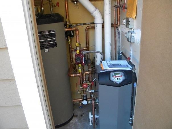 Technician performing maintenance on a heating boiler, inspecting and servicing its components for optimal functionality.