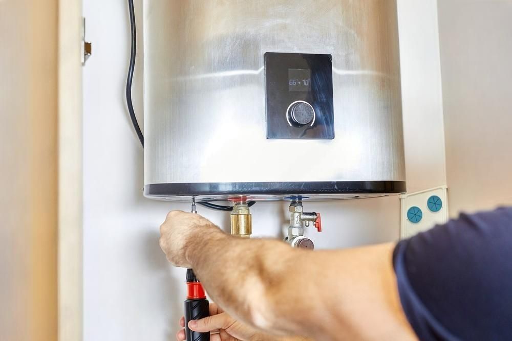 Plumber sets up electric heating boiler at home bathroom.