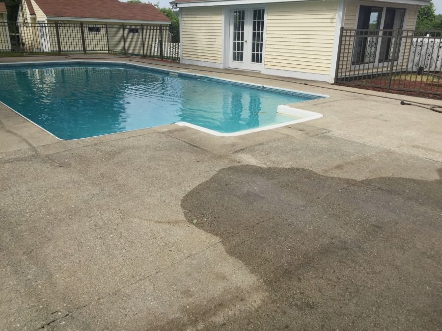 Backyard swimming pool beside a concrete patio and house exterior