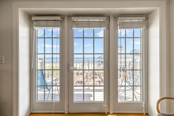 A room with three windows and a view of the ocean.