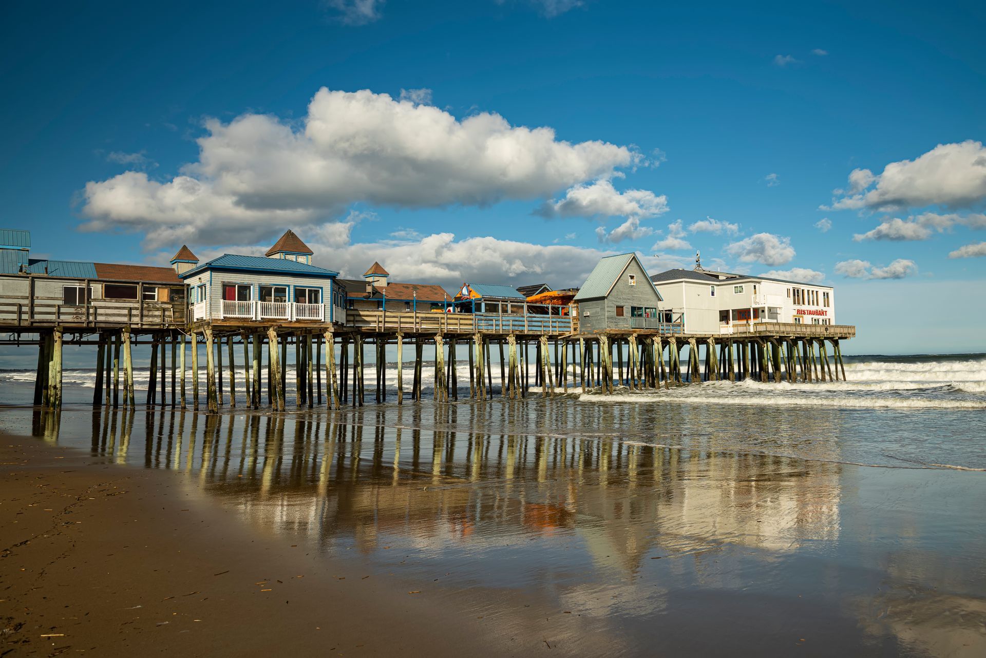 A pier sitting on top of a sandy beach next to the ocean.
