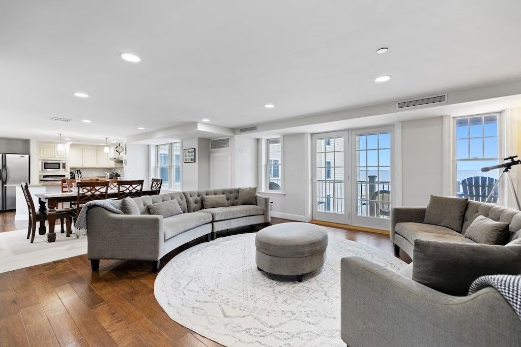 A living room with a large sectional couch , chairs , and ottoman.