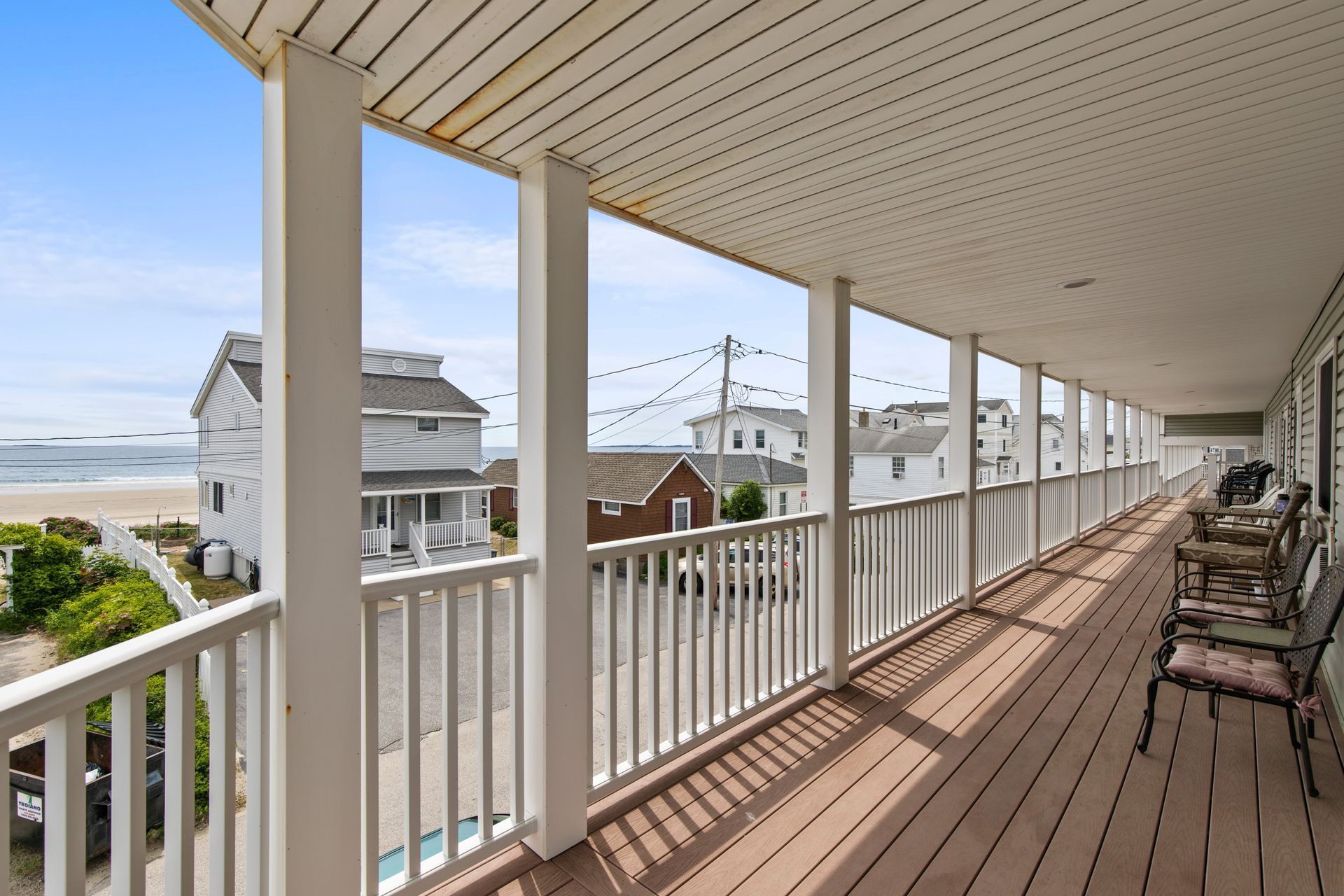A long balcony with a view of the ocean and houses.