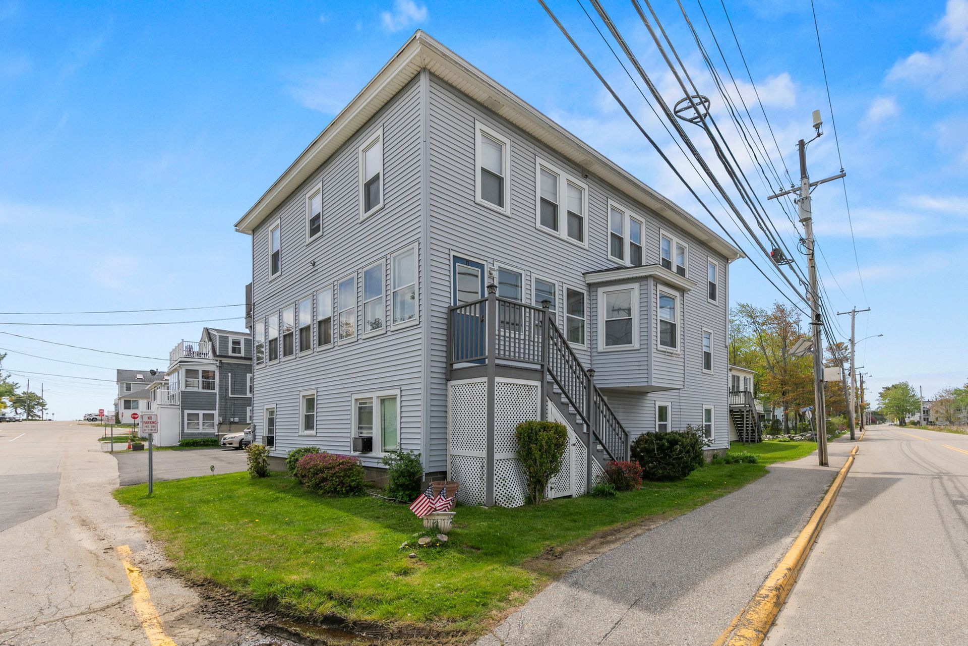 Gray two-story house on a corner lot with white trim, small porch, and power lines overhead