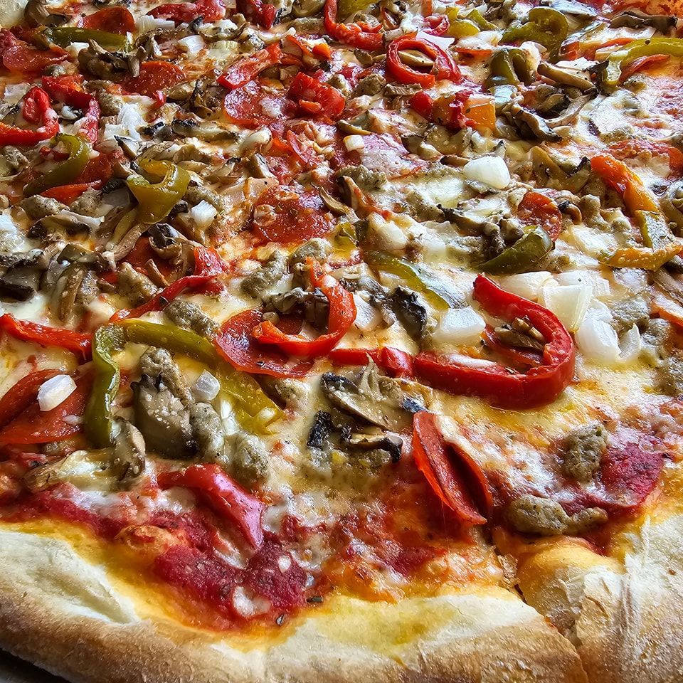 A pizza with pepperoni , mushrooms , cheese and peppers on it.