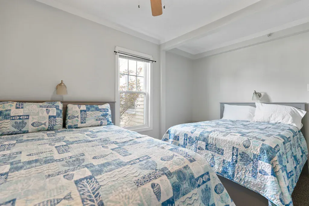 A bedroom with two beds and a ceiling fan.