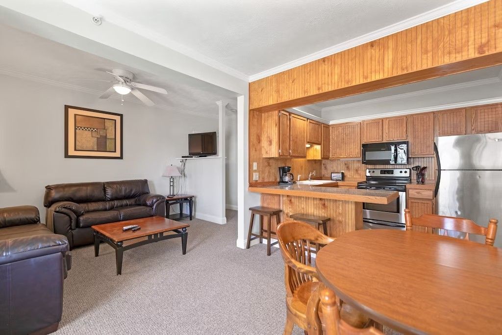 A living room with a couch , table , chairs and a kitchen.