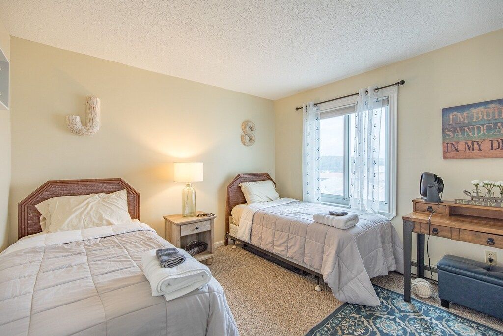 A bedroom with two beds , a desk and a window.
