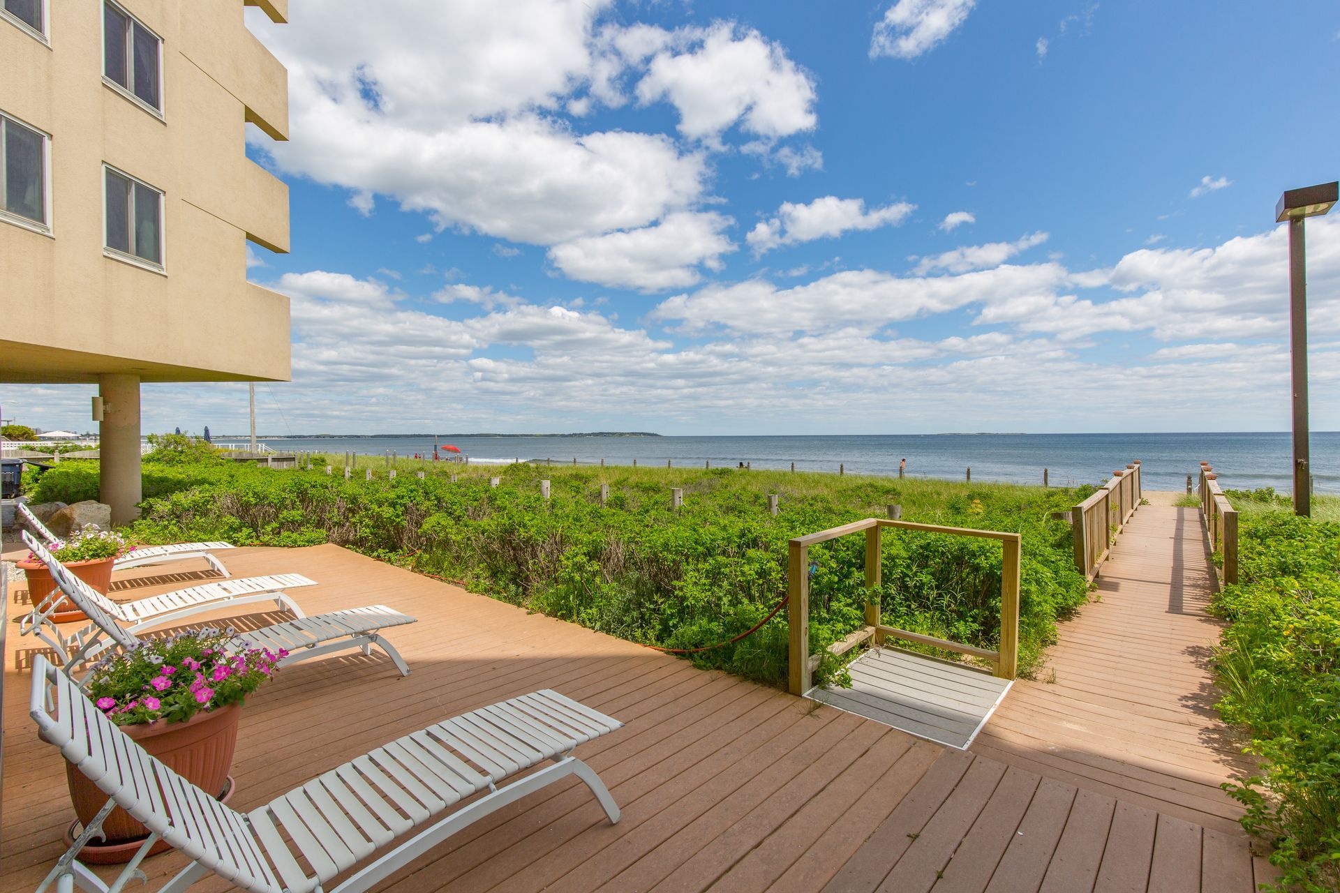 A deck with chairs and a walkway leading to the ocean