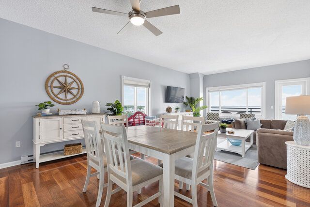 Bright dining room and living area with white furniture, hardwood floors, and a coastal-style decor.