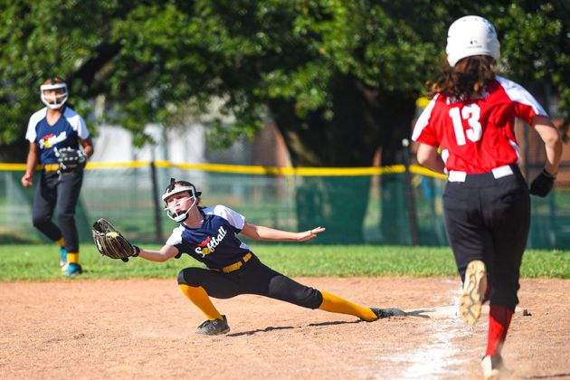 Baseball player sliding into home plate, catcher in front. Blue and gold uniforms, action shot.