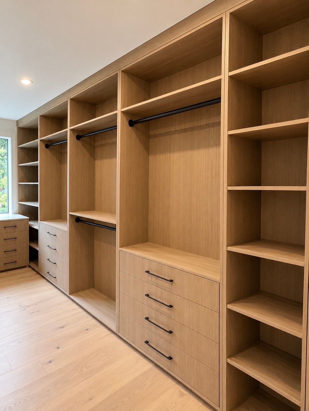 Built-in wooden walk-in closet with open shelves, drawers, and hanging rods in a bright room
