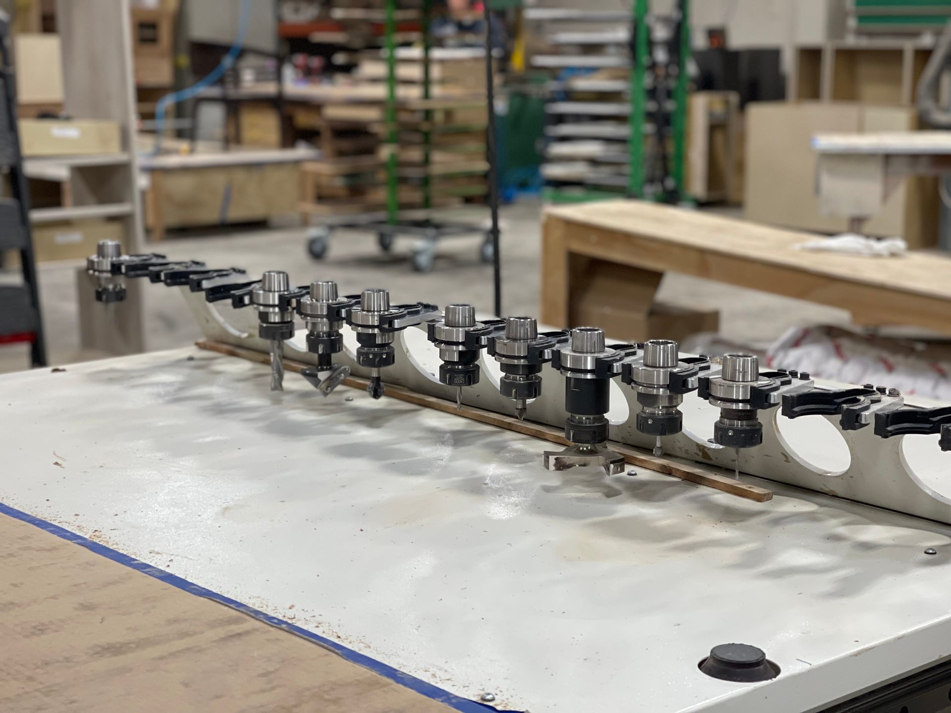 Close-up of a woodworking machine with multiple drill bits in an industrial setting.