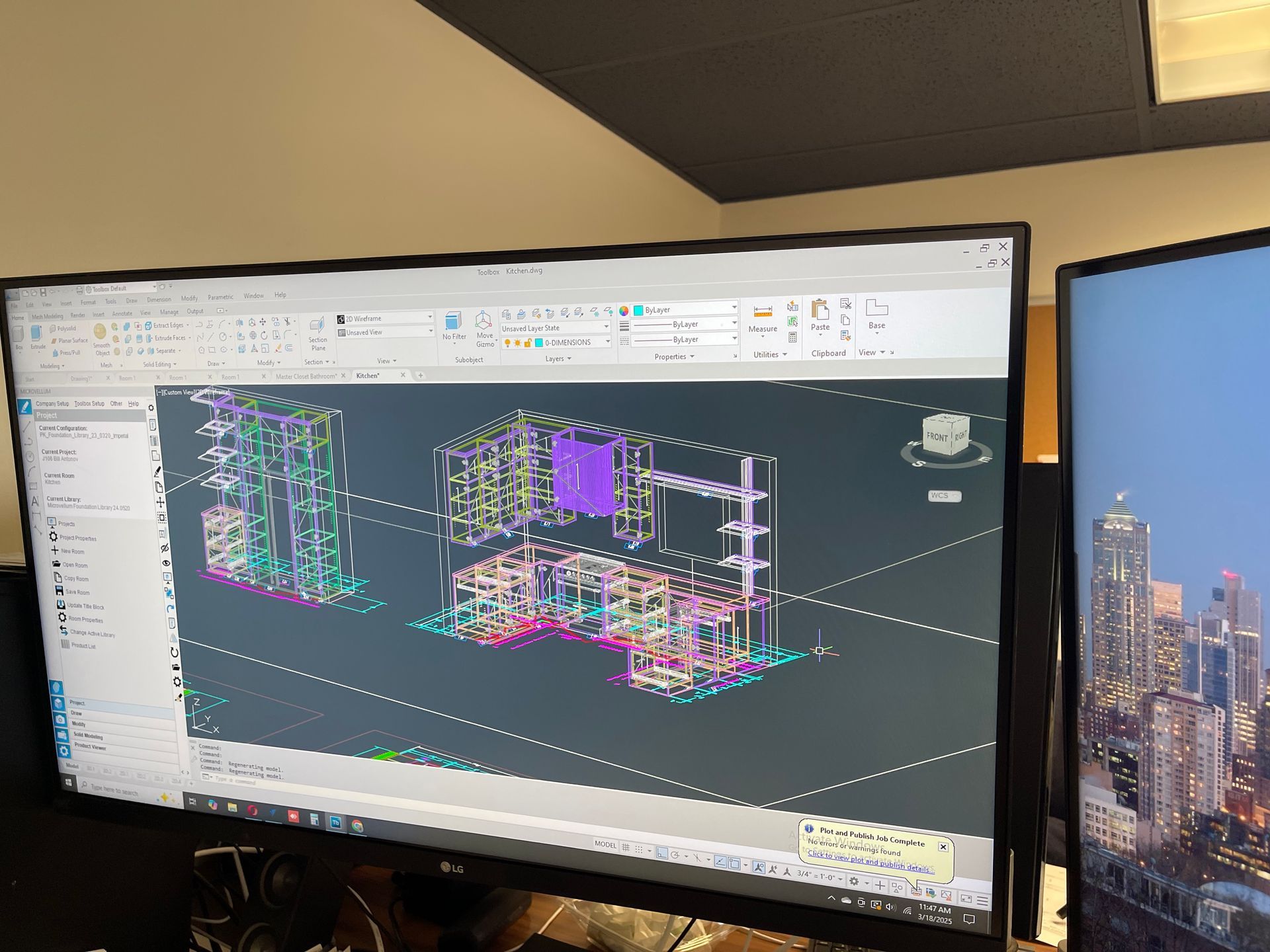 A computer screen displaying a 3D CAD design, with a second screen showing a cityscape.