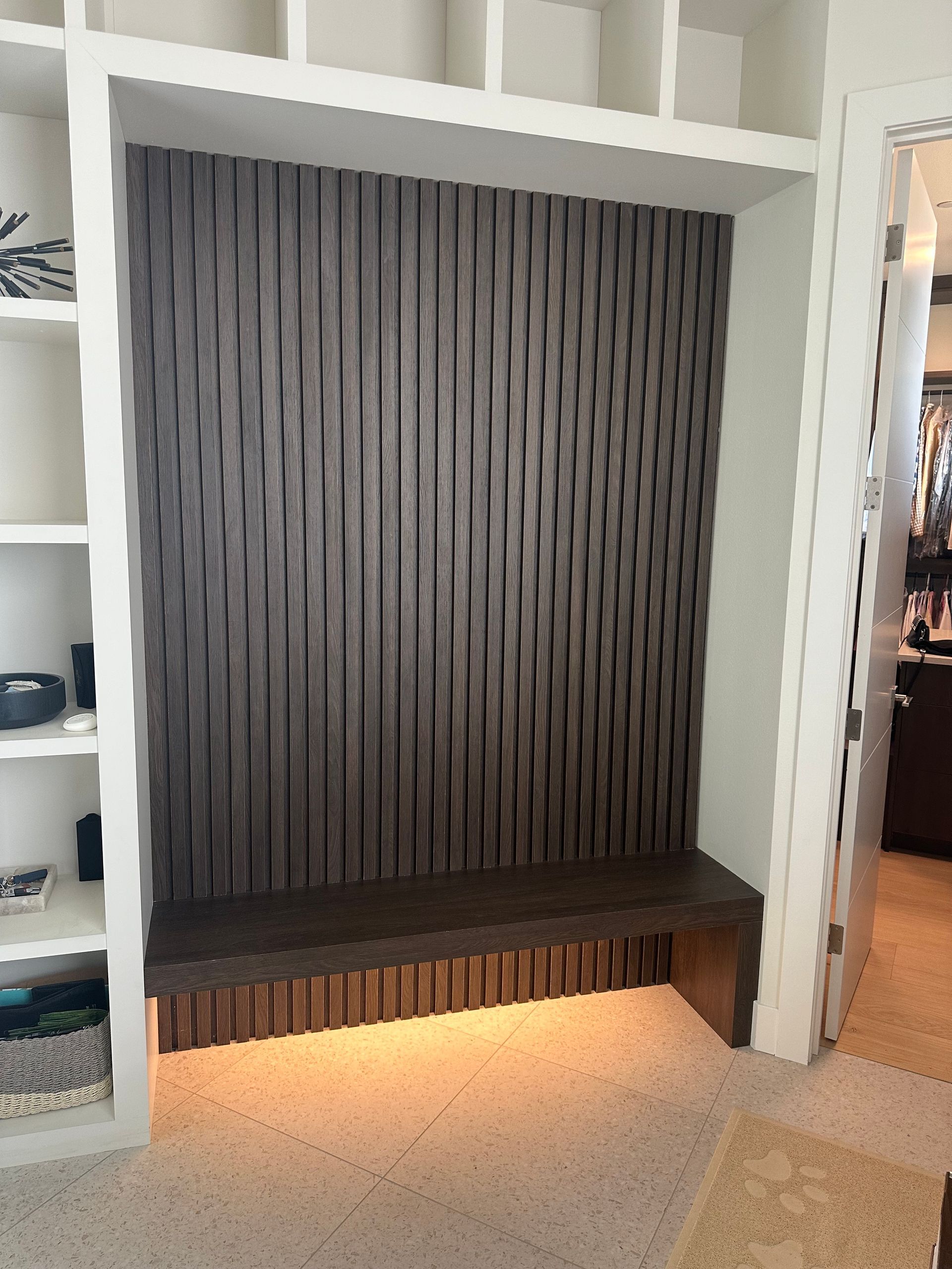 Built-in dark striped bench nook with warm underlighting and white shelving