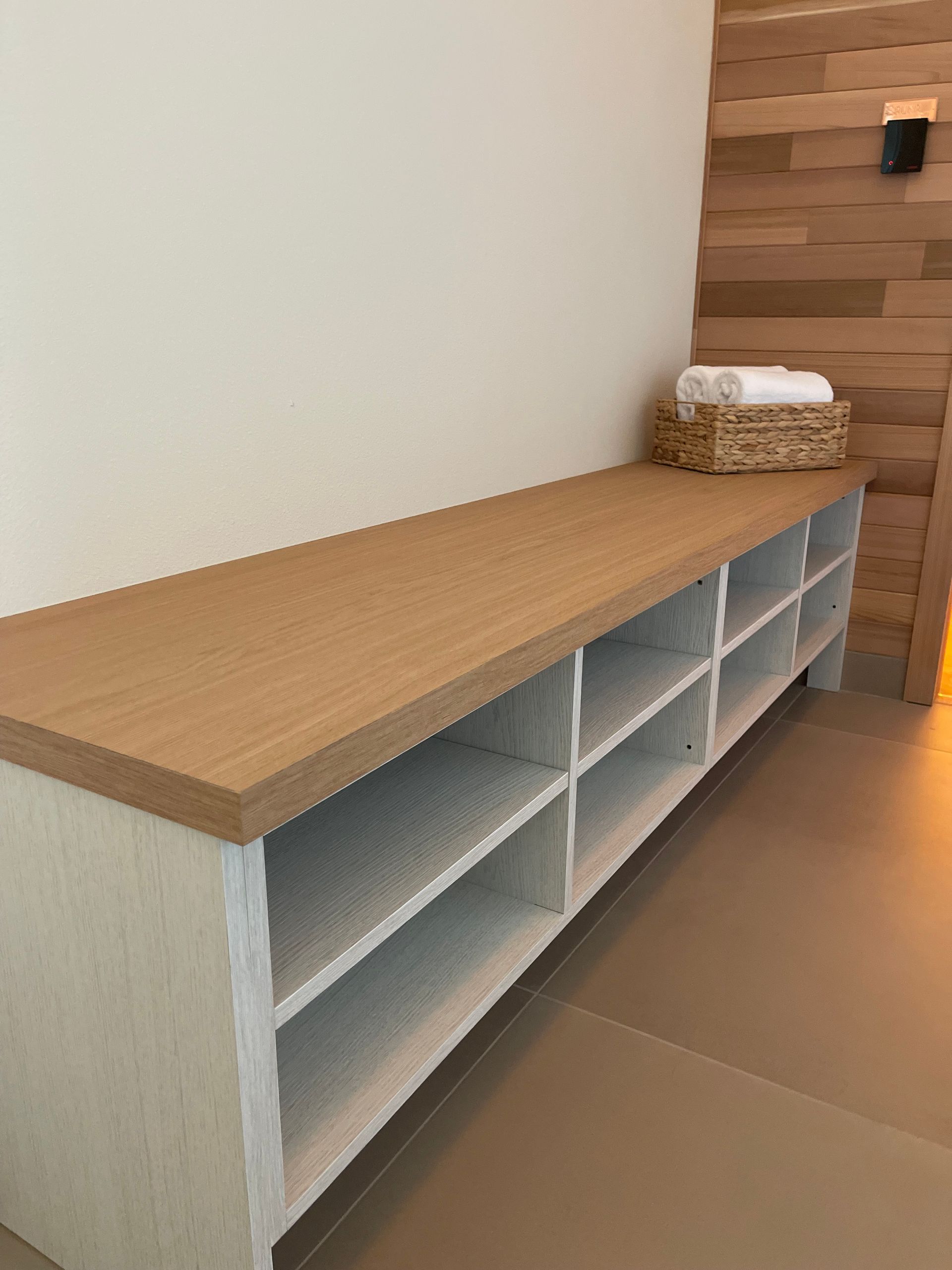A white, multi-cubby storage bench with a light wood top . Pro-tech woodworking in Portland