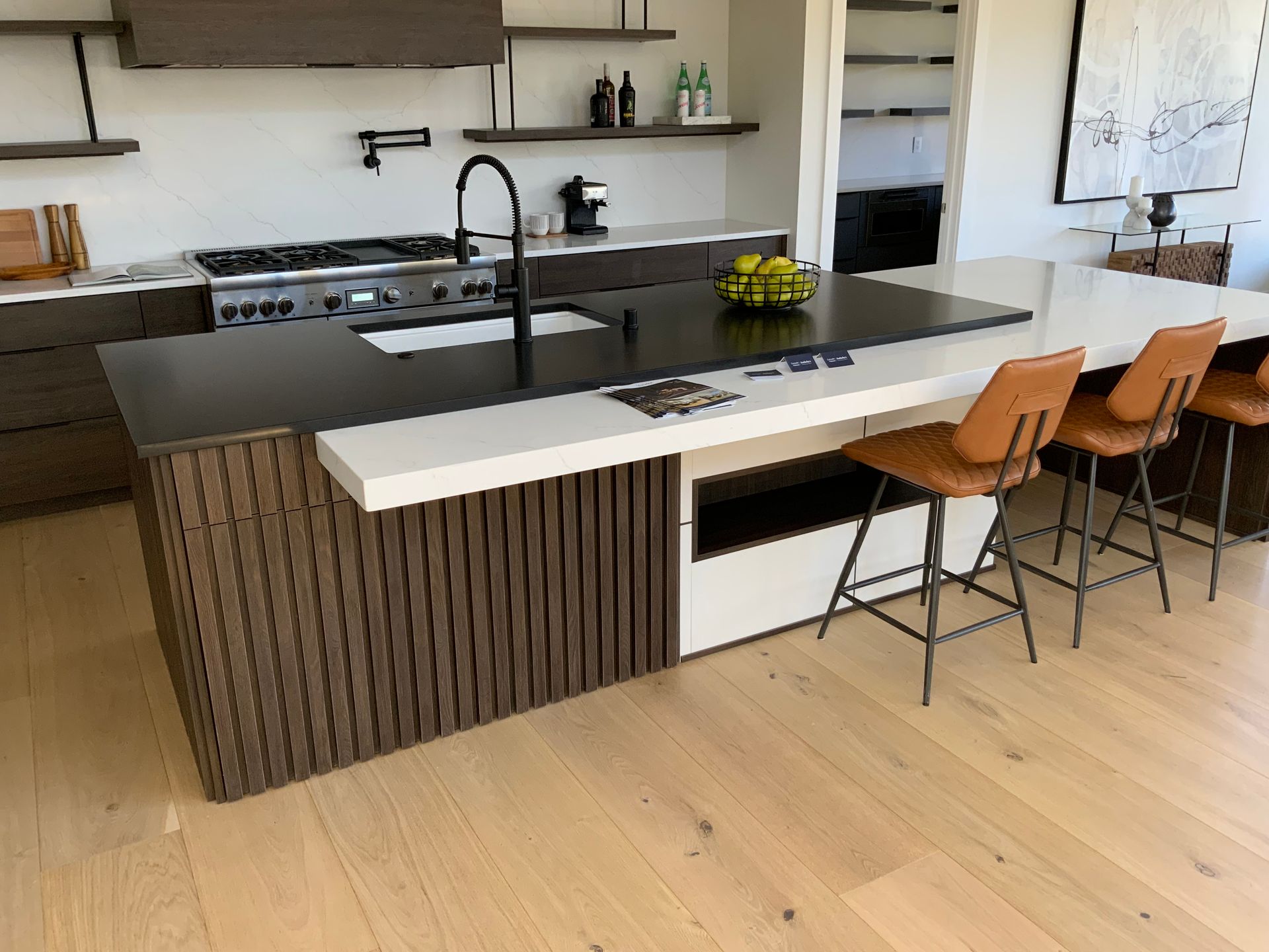 Modern kitchen with dark wood cabinetry, a black island, and bar stools.