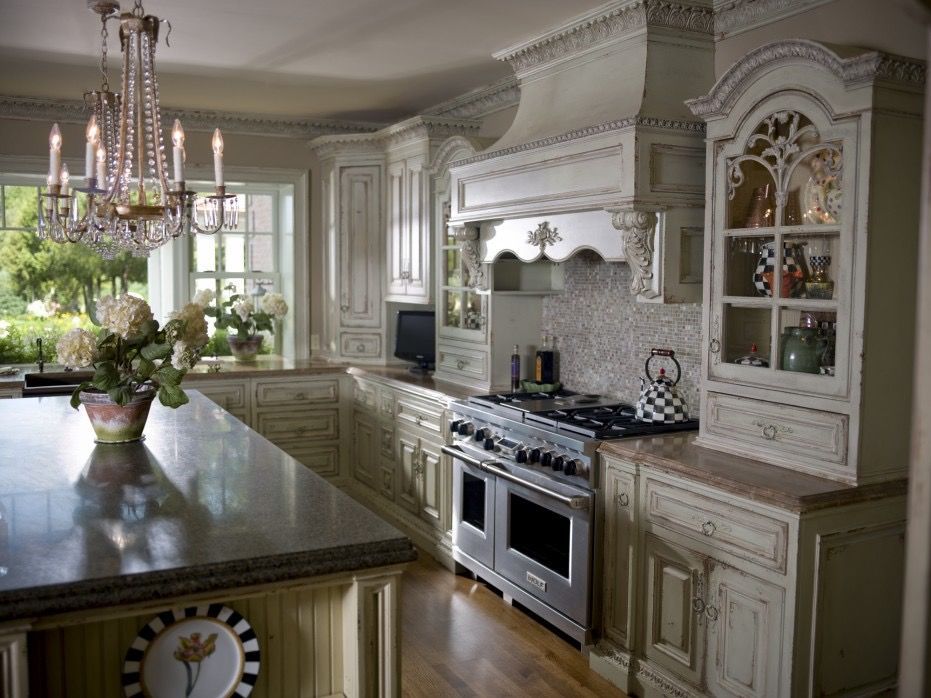 Elegant kitchen with ornate cream cabinetry, island, and stainless steel range.