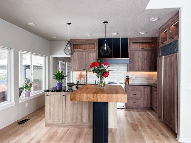 Modern kitchen with wood cabinets, island, and light wood floors. Red flowers on the island.