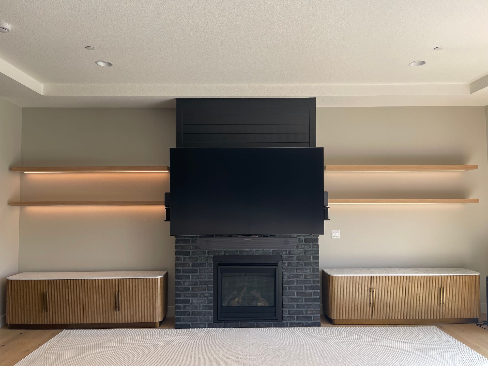 dark fireplace, flanked by wooden cabinets and floating shelves with soft lighting in Portland, from Pro-techwoodworkig