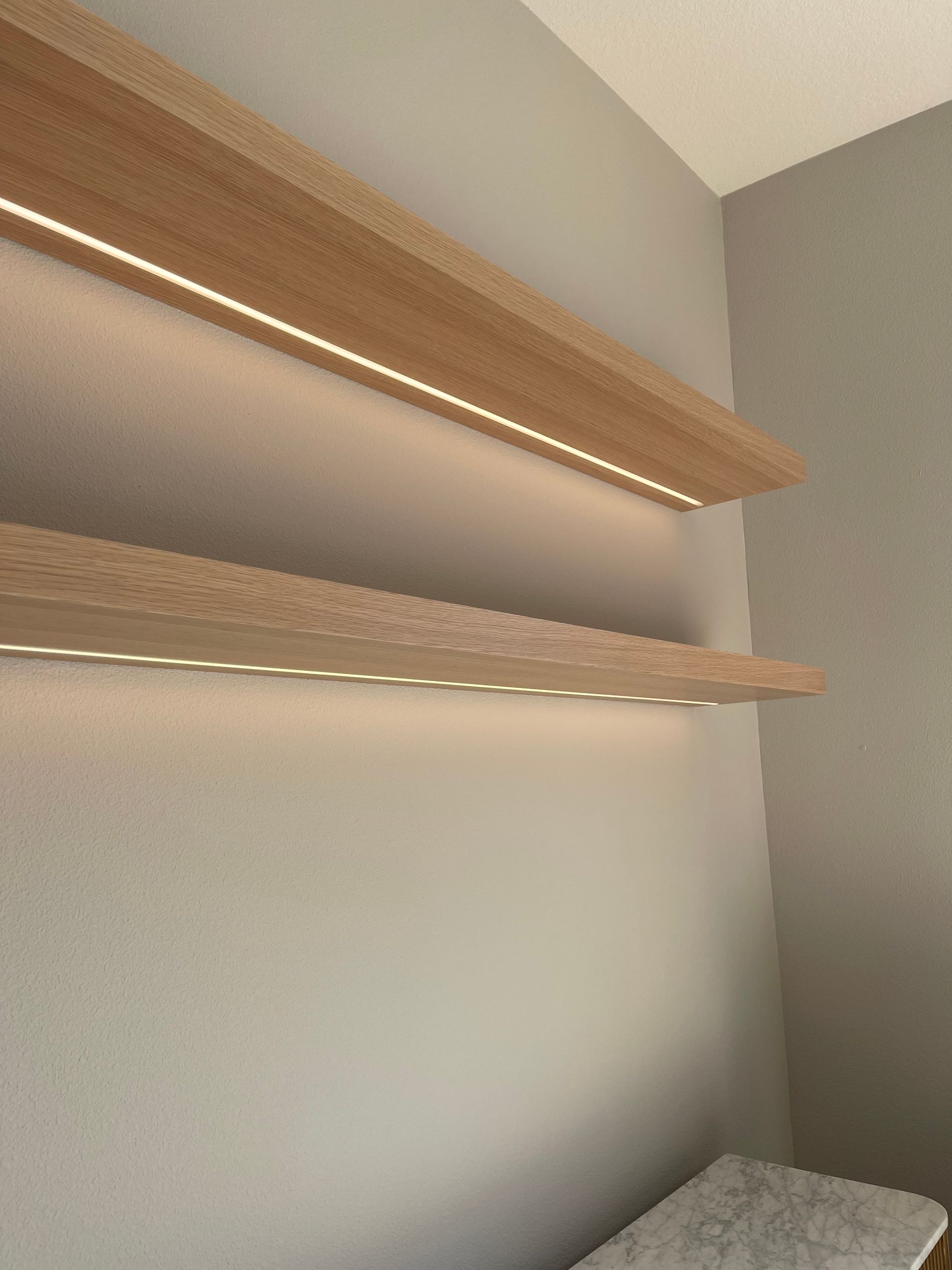 Empty corner with two wooden floating shelves and a bed edge below in Portland, from Pro-techwoodworkig