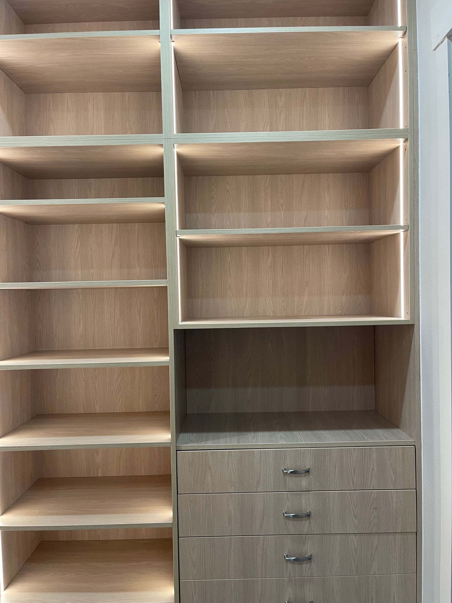 Light wood closet shelving unit with cabinets, drawers, and open storage compartments